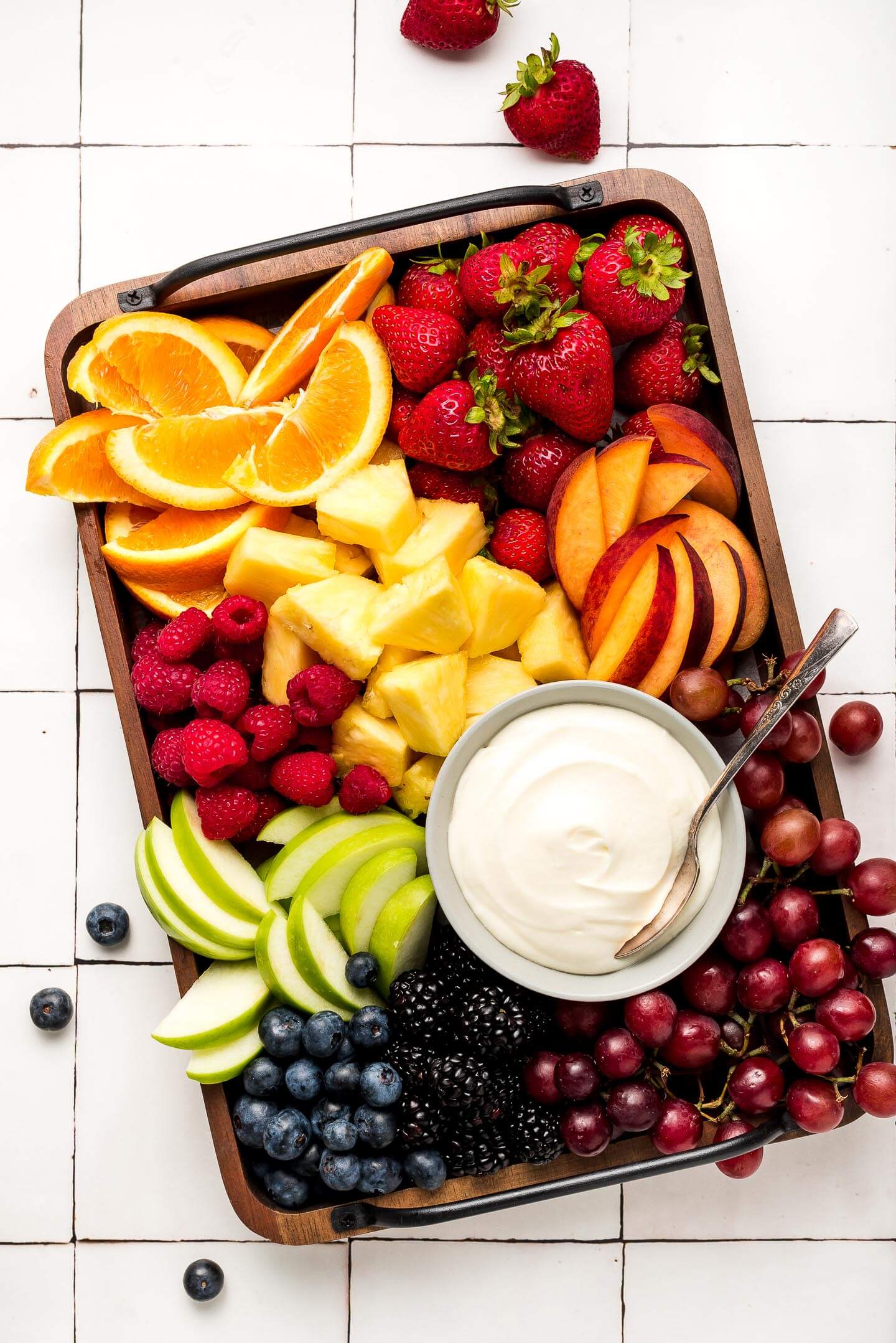 A tray full of fruit and cream cheese dip.