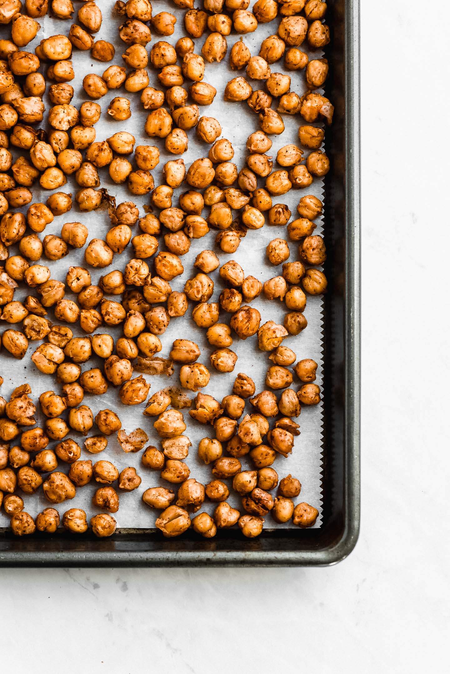 Roasted Chickpeas on a parchment lined baking sheet seasoned with spices.
