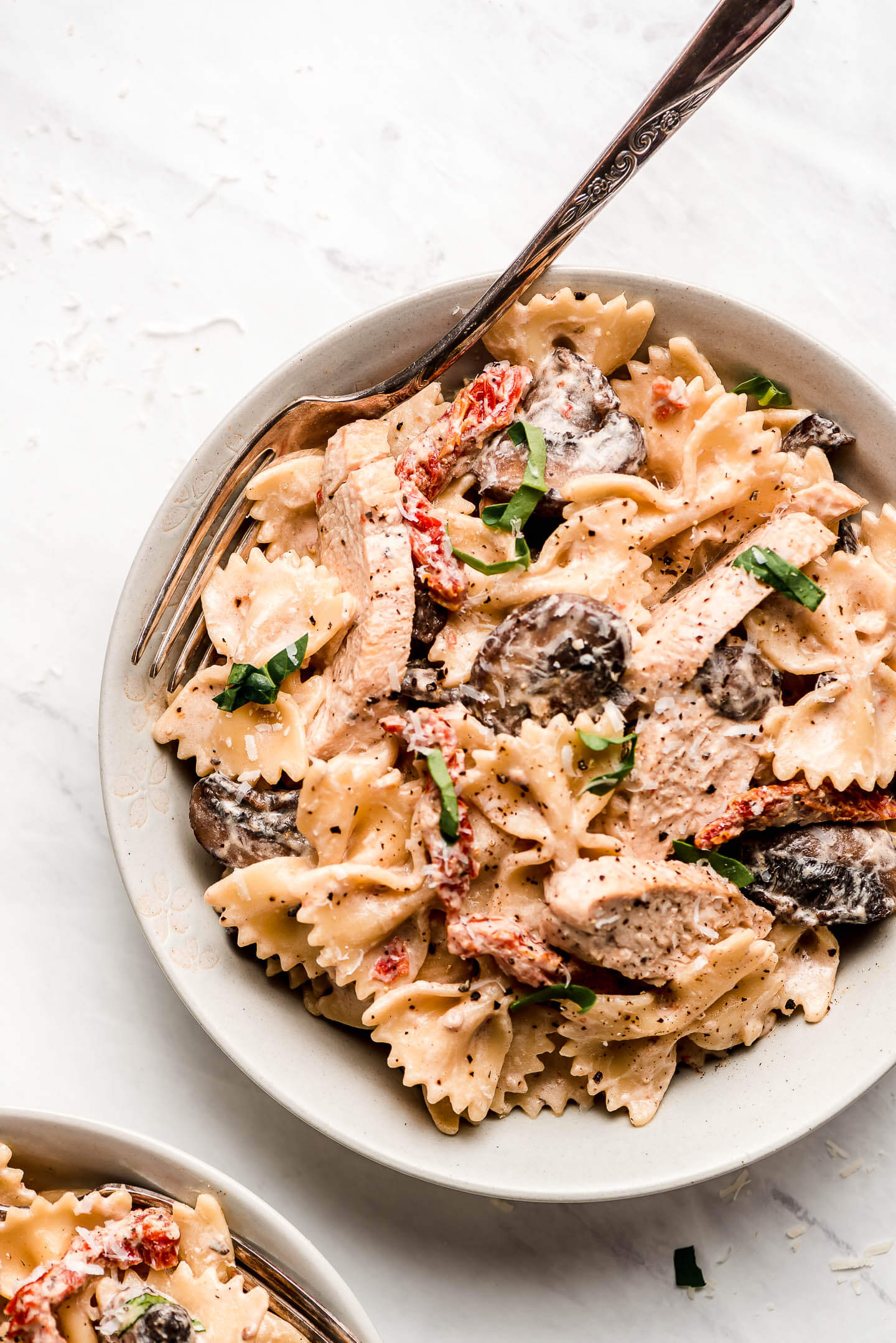A bowl of creamy Chicken Pasta Milano with sun dried tomatoes, chicken and mushrooms. 