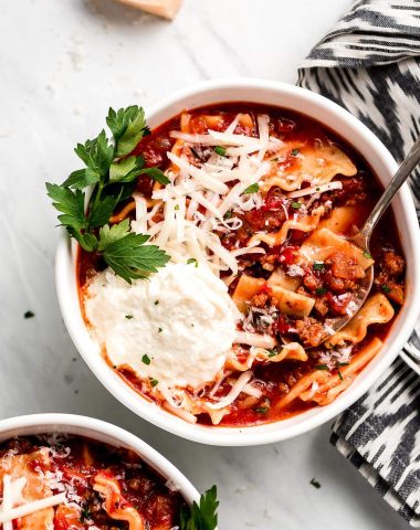 Two bowls of Lasagna Soup topped with ricotta, mozzarella, parmesan, and parsley.