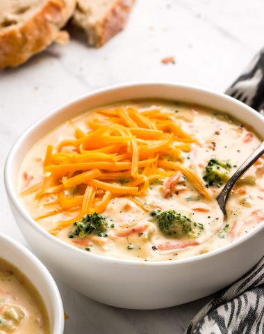 A bowl of Panera Broccoli Cheese Soup topped with shredded cheddar cheese.