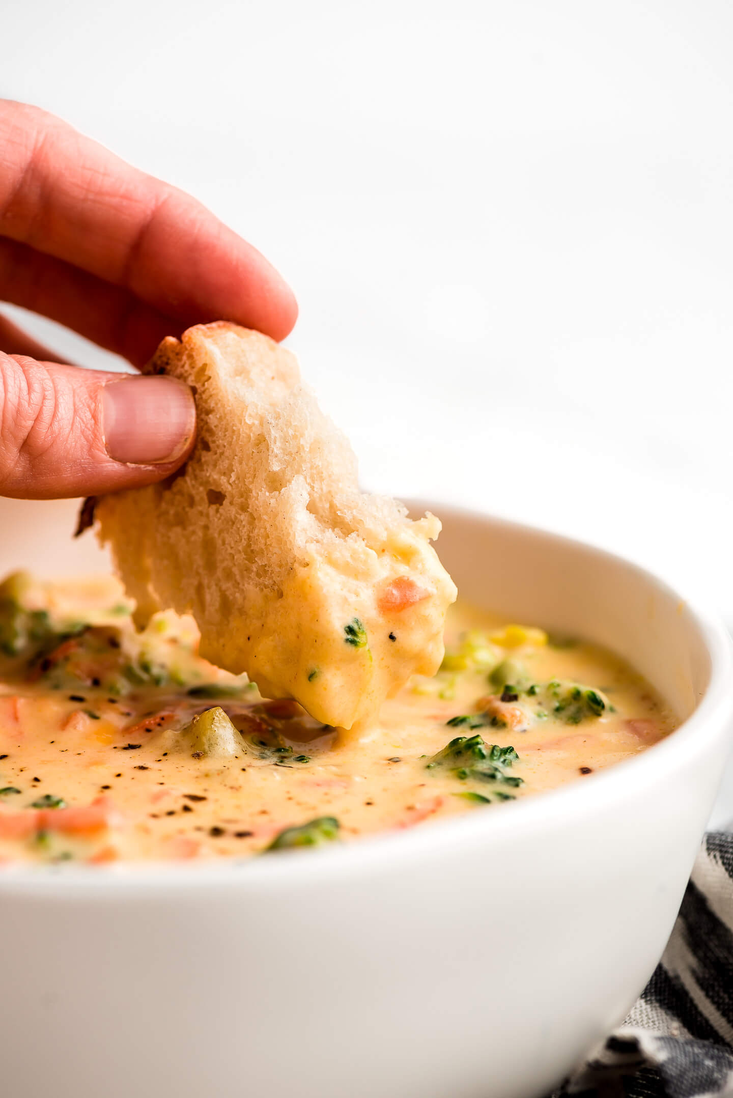 Dipping a piece of bread in thick and creamy Broccoli Cheddar Soup.