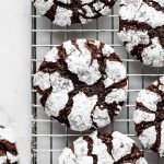 Brownie cookies with powdered sugar on cooling rack.
