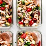 Four glass meal prep containers of chicken couscous salad.