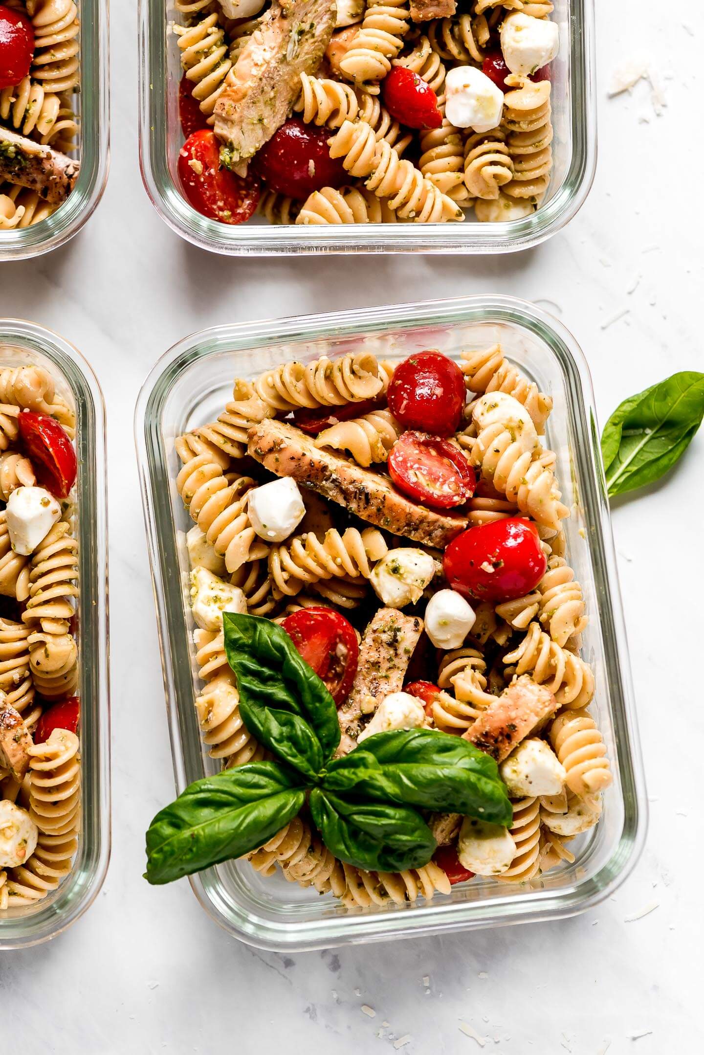 Multiple glass meal prep containers with Pesto Pasta Salad.
