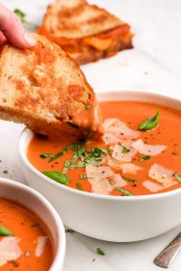 Dipping a grilled cheese sandwich into a bowl of Tomato Basil Soup.