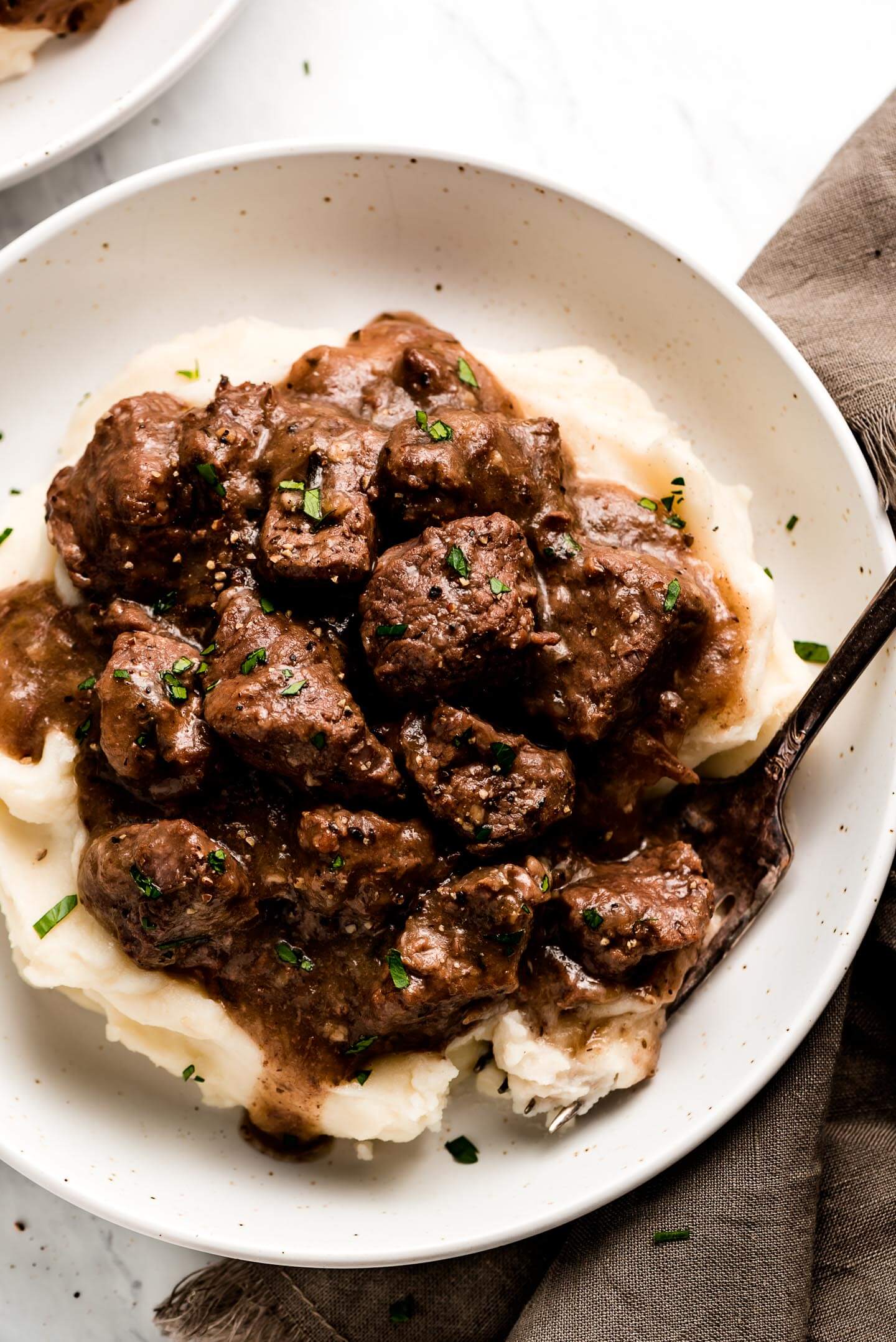 A bowl of Instant Pot Beef Tips & Gravy over a bed of mashed potatoes.