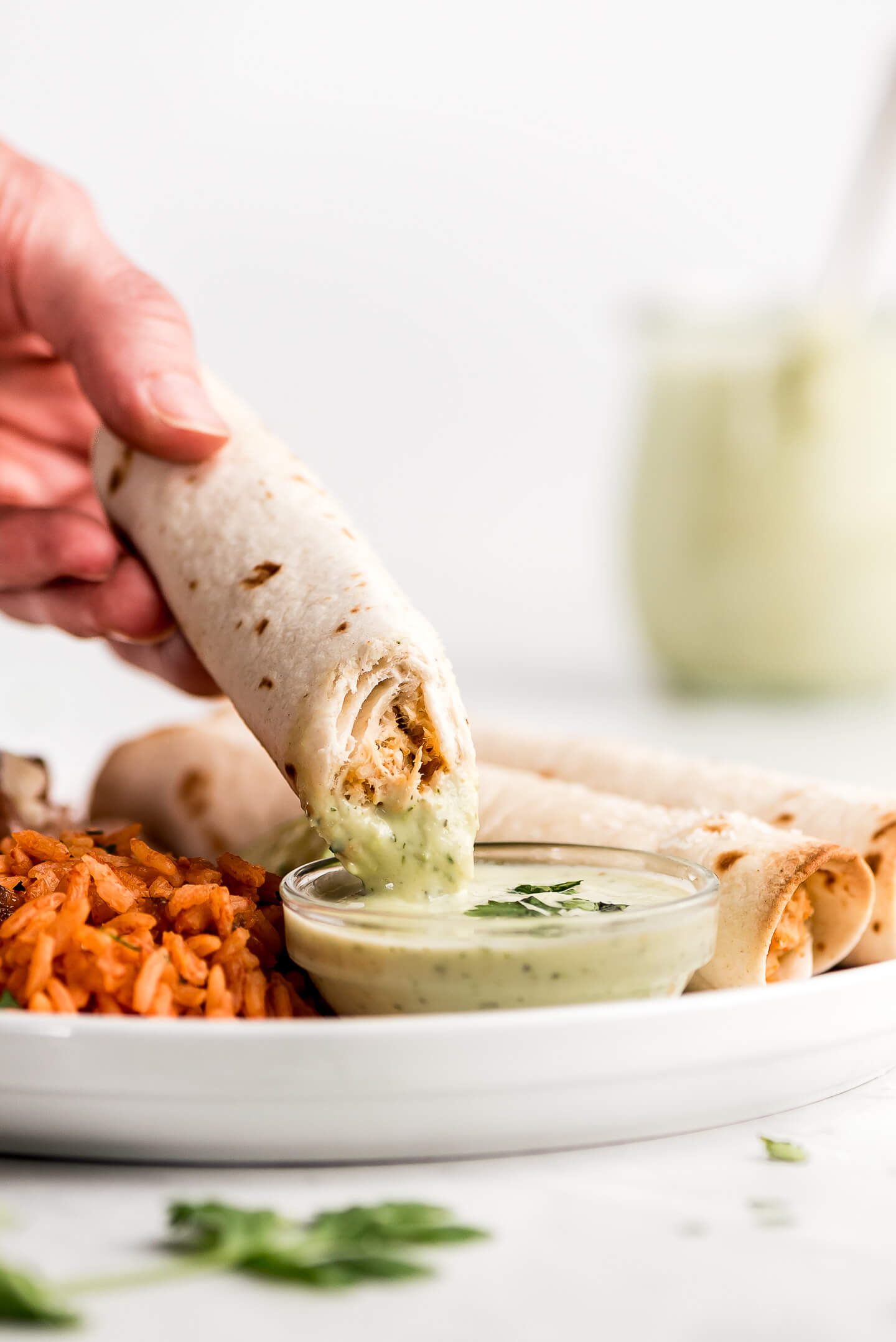 Close up shot of dipping a Baked Chicken Taquito into Creamy Cilantro Lime Dressing.
