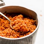 A spoonful of Spanish Rice in a pot.