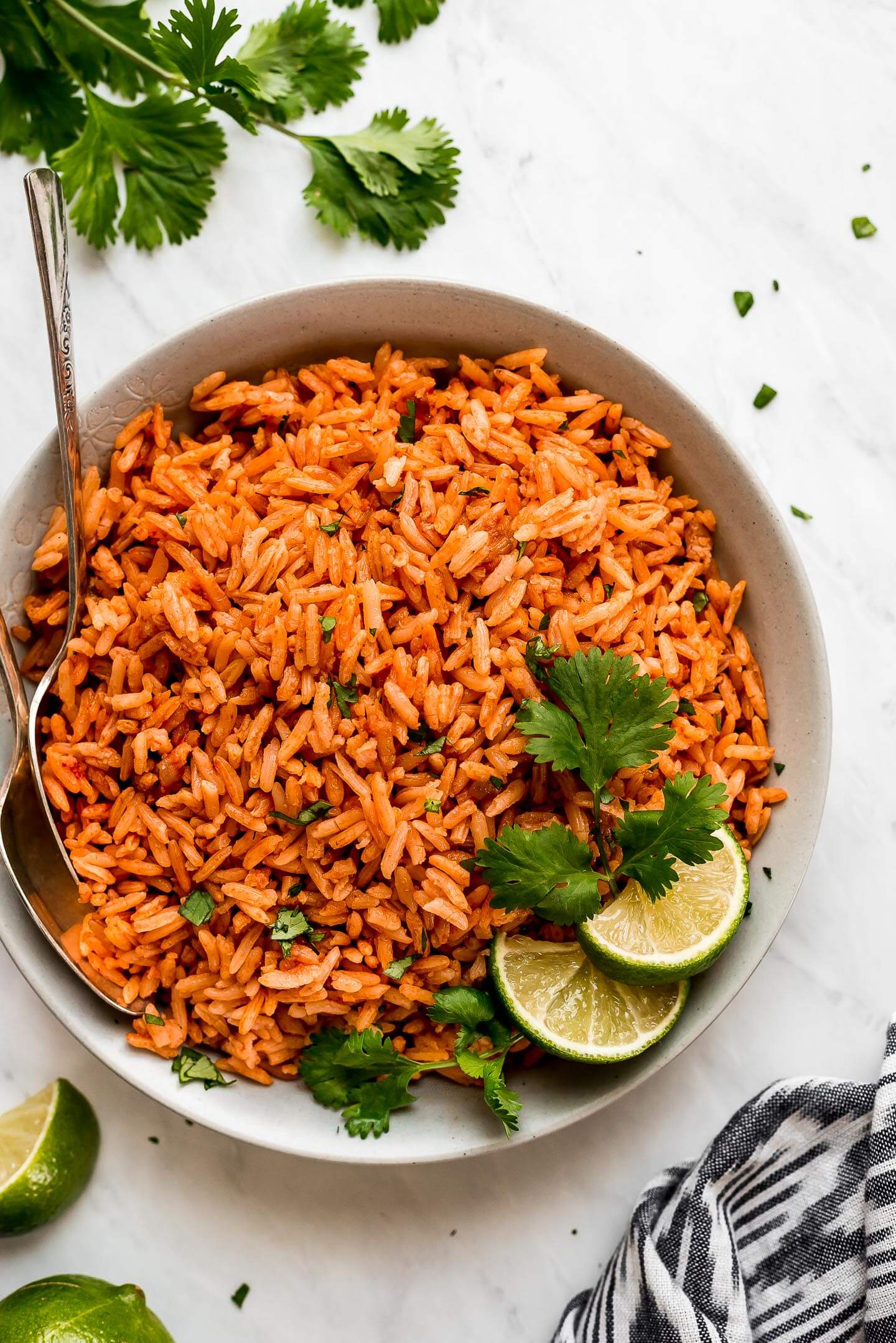 A bowl of Spanish Rice garnished with cilantro and lime wedges on the side.
