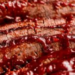 Close up shot of sliced Beef Brisket with barbecue sauce on the top edges.