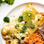 A plate with Honey Lime Chicken Enchiladas, Spanish Rice, and Refried Beans.
