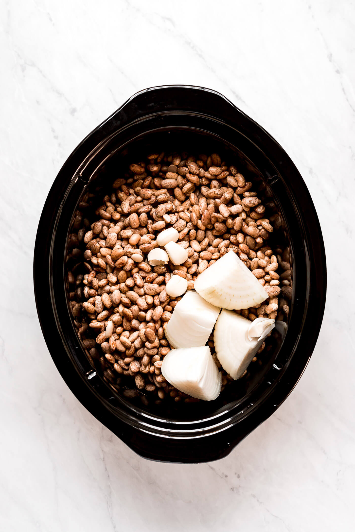 Pinto beans, garlic, and onion in a slow cooker.