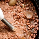 Puréeing pinto beans in a Crock-Pot using a hand blender.