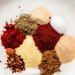 Various spices in a shallow white bowl for Taco Seasoning.
