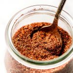 A jar of Homemade Taco Seasoning with a spoon in it.