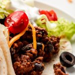 Soft shell Ground Beef Tacos filled with ground beef, beans, cheese, lettuce, olives, tomatoes, and sour cream.