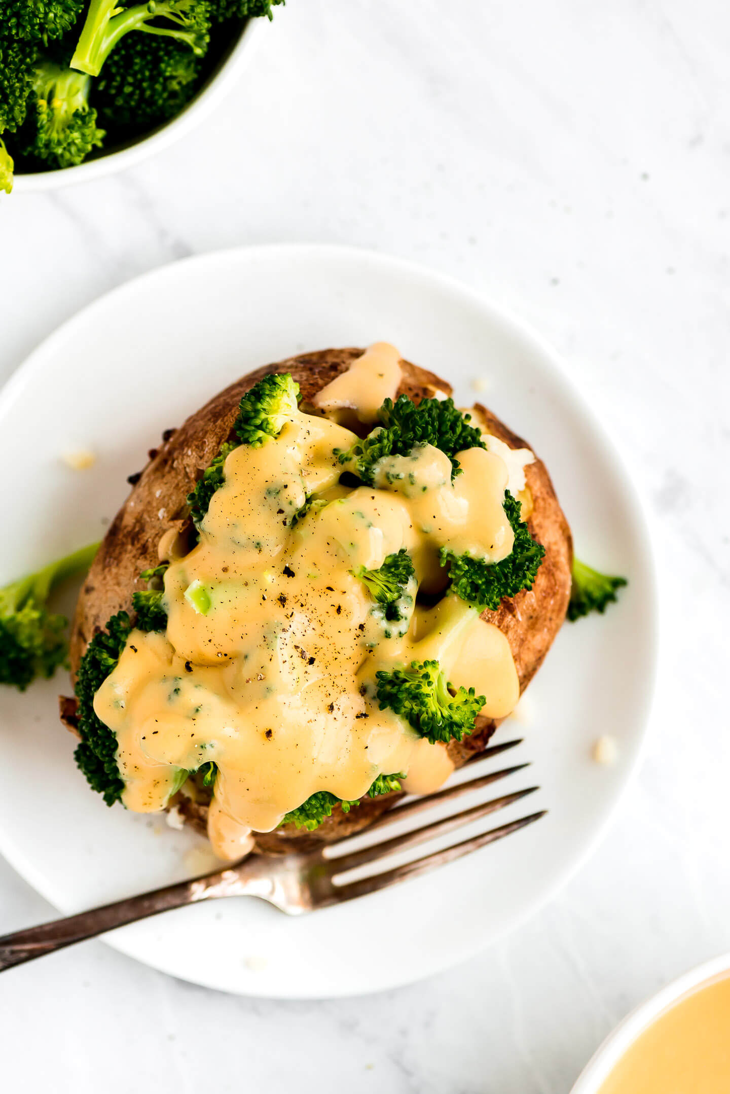 Top view of a baked potato topped with broccoli & cheese sauce.