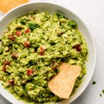 Top view of a large bowl of Homemade Guacamole with a chip in the side.