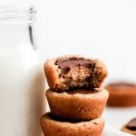 Peanut Butter Cup Cookies stacked on top of each other with a bit out of the top one and a bottle of milk to the side.