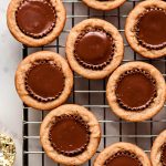 Peanut Butter Cup Cookies on a cooling rack with wrapped Reese's to the side.