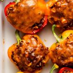 Halved Stuffed Bell Peppers topped with melted cheese in a white pan.