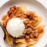 Close up shot of Apple Crumble with a scoop of ice cream on top.