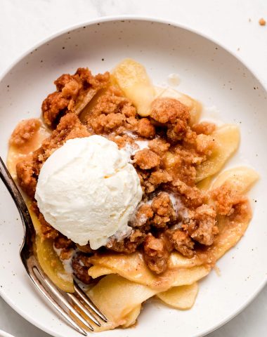 Close up shot of Apple Crumble with a scoop of ice cream on top.