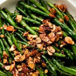 Haricots Verts in a serving bowl and topped with toasted almonds and lemon zest.