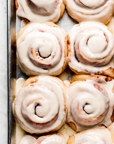 Frosted cinnamon rolls on a baking sheet.