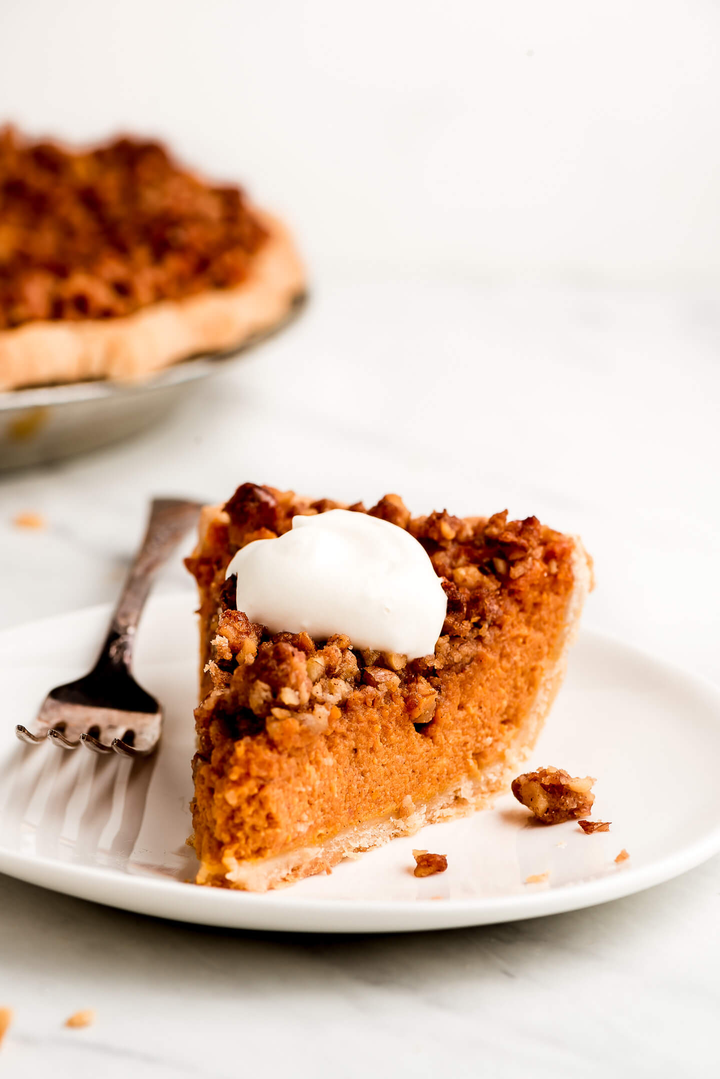 A slice of Pumpkin Streusel Pie garnished with whipped cream on a plate.
