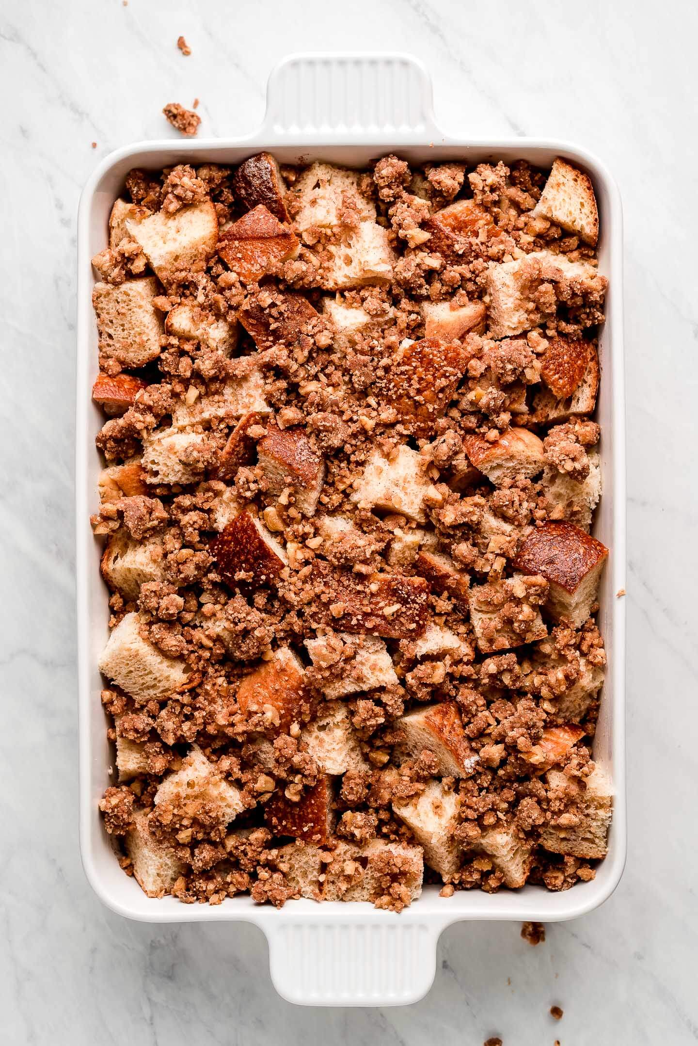 Cubes of bread in a baking pan with streusel on top.