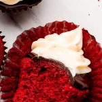 Red cupcake on its side with a bite taken out.