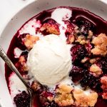 Close up of warm Blackberry Cobbler topped with vanilla ice cream.