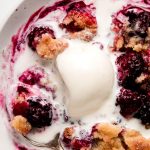 Warm Blackberry Cobbler with half melted ice cream on top.