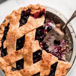 Blueberry Pie with a few pieces removed and one on a plate to the side.