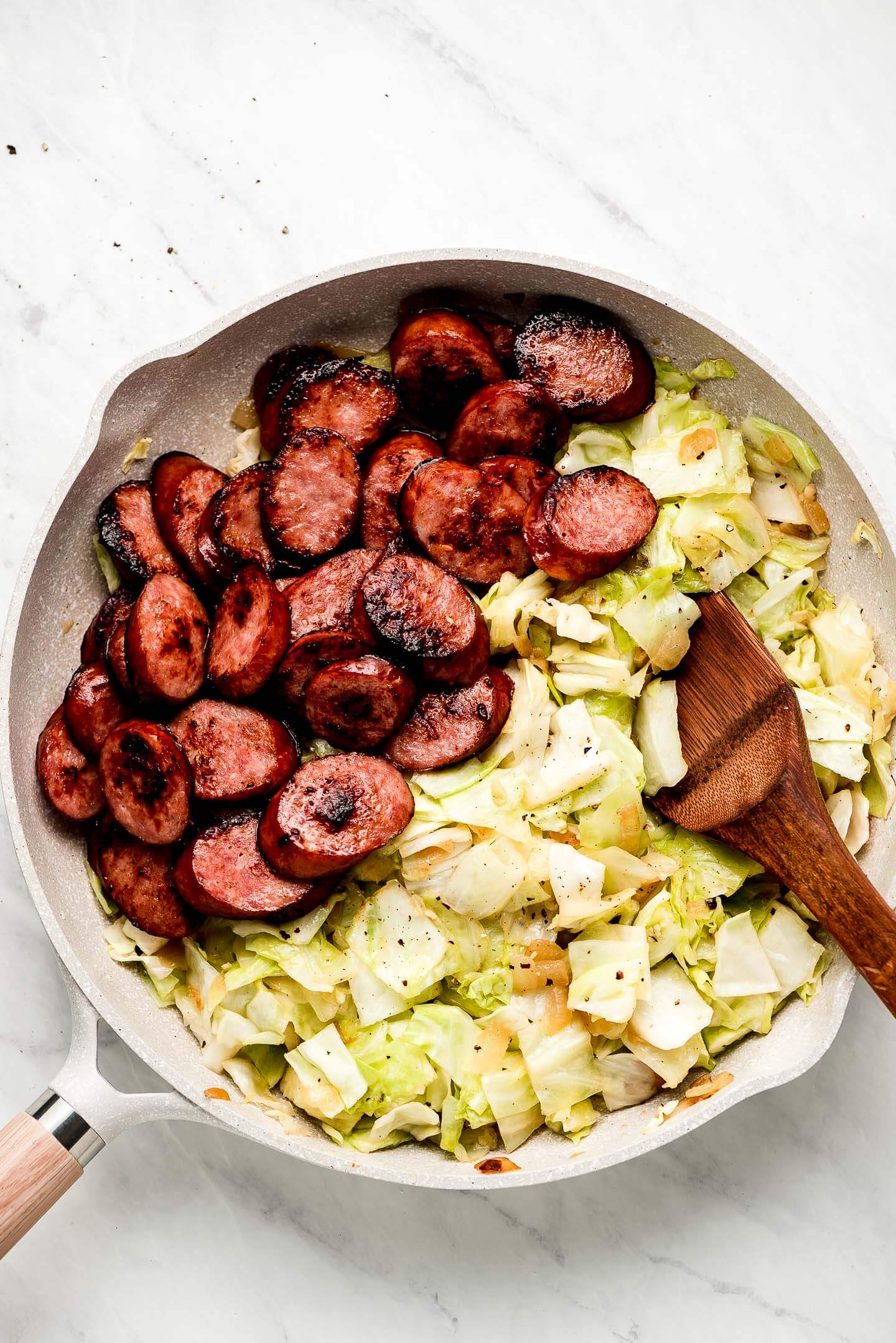 Smoked kielbasa and cooked cabbage in a skillet.