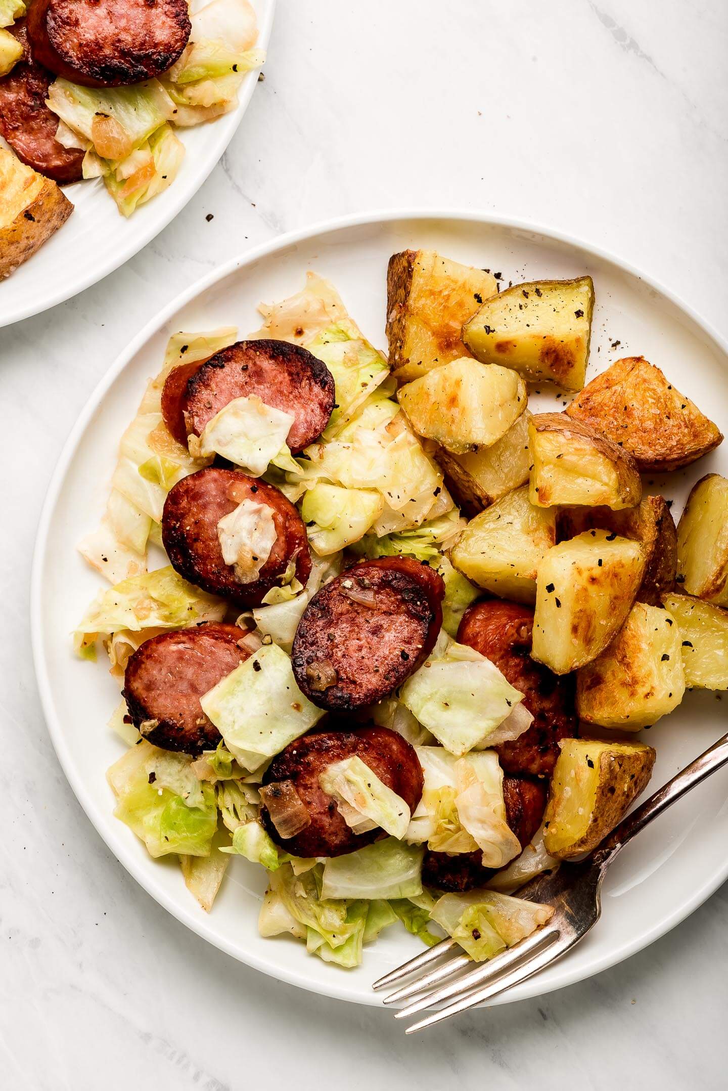 Cabbage and Sausage on a plate with crispy potatoes.