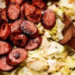 Cooked cabbage and onions next to seared smoked sausage.