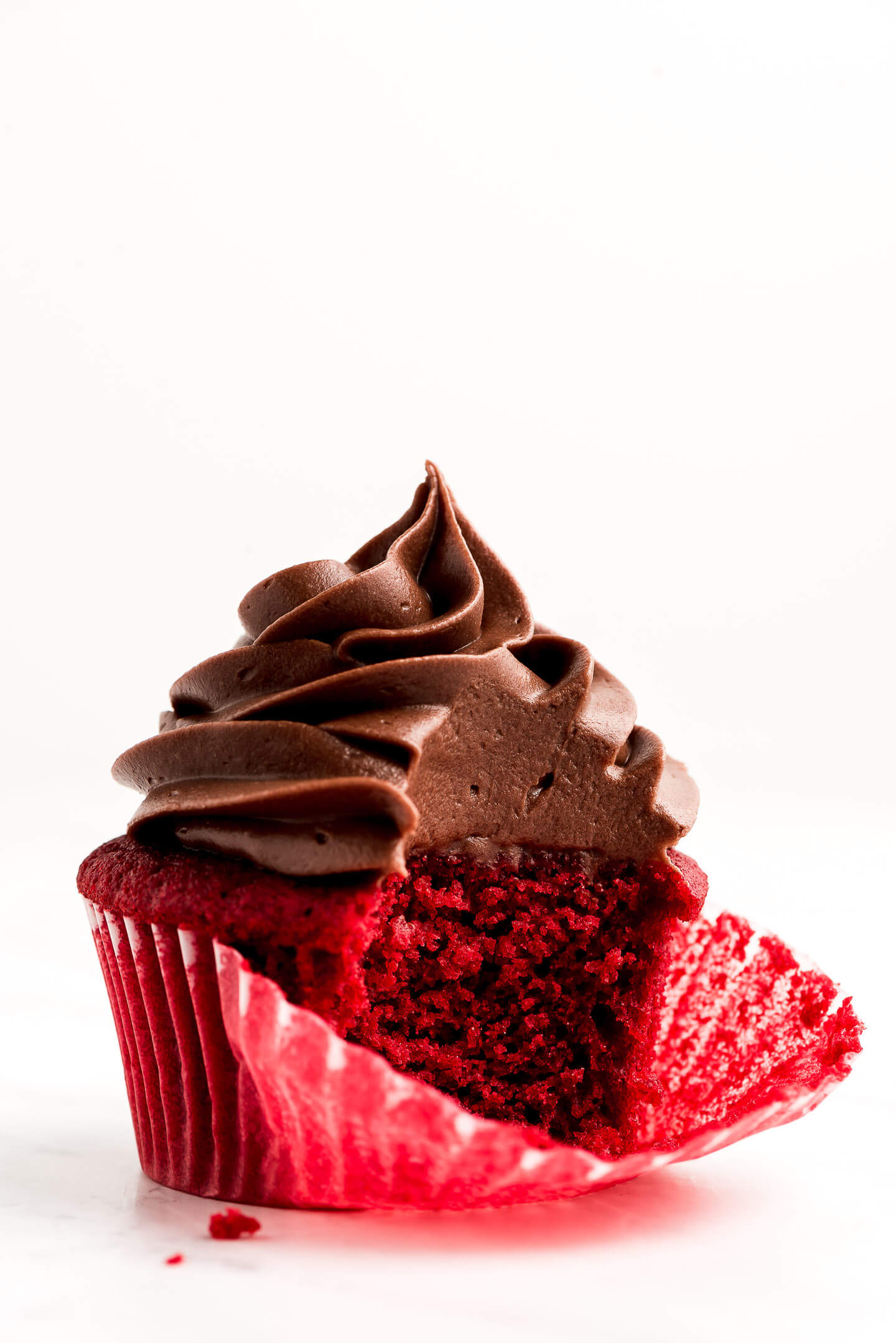 Red Velvet Cupcake with Chocolate Frosting with a bite take out.