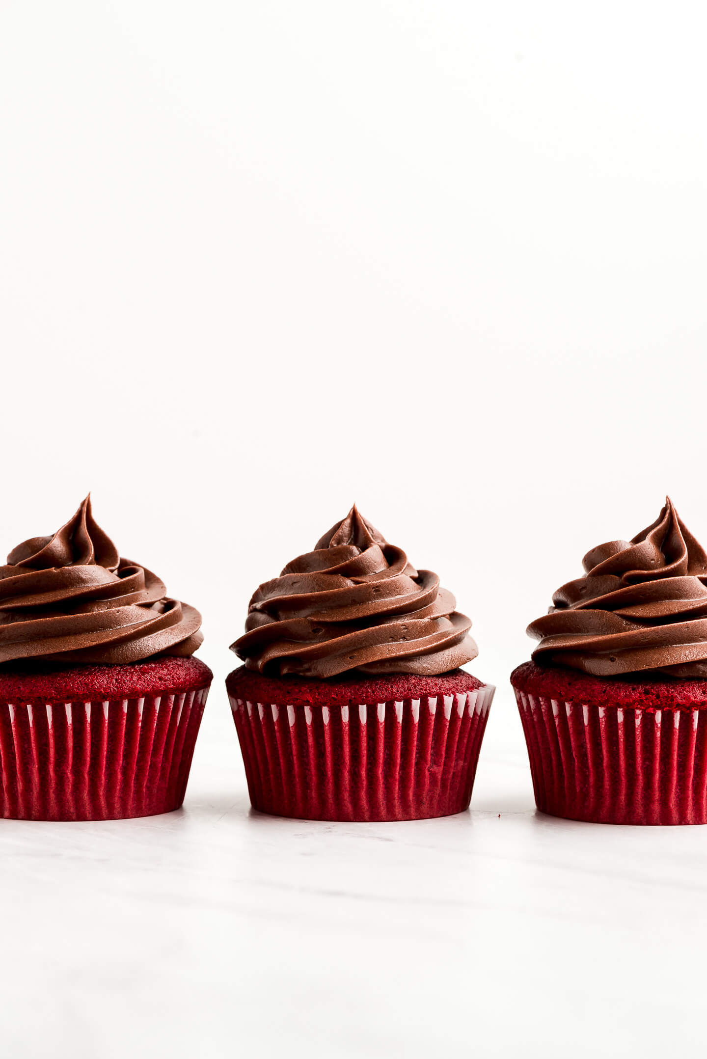 Three Red Velvet Cupcakes topped with Chocolate Cream Cheese Frosting.