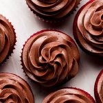 Chocolate Cream Cheese Frosting swirled on red cupcakes.