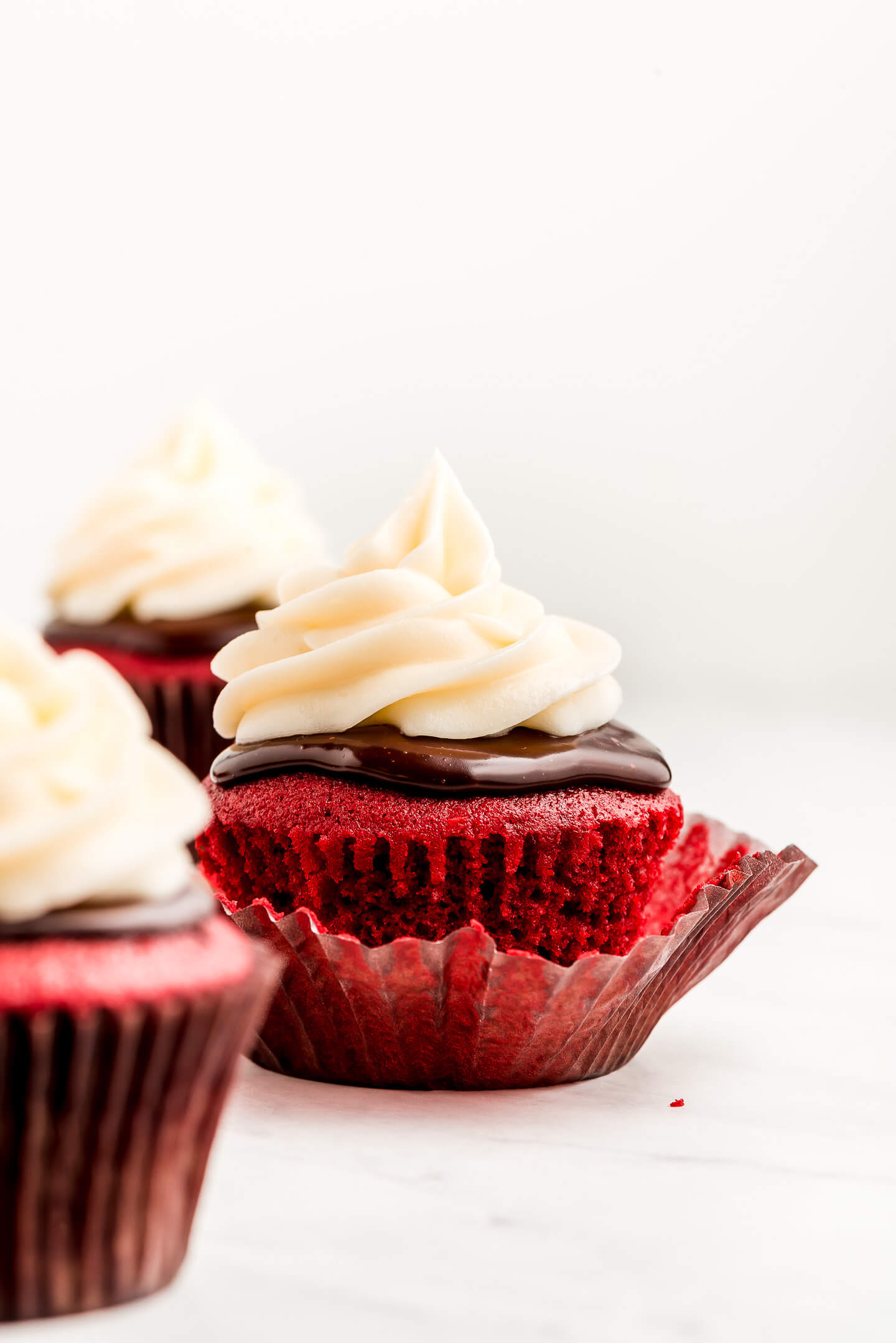 An unwrapped Red Velvet Cupcake with Cream Cheese Frosting and ganache.