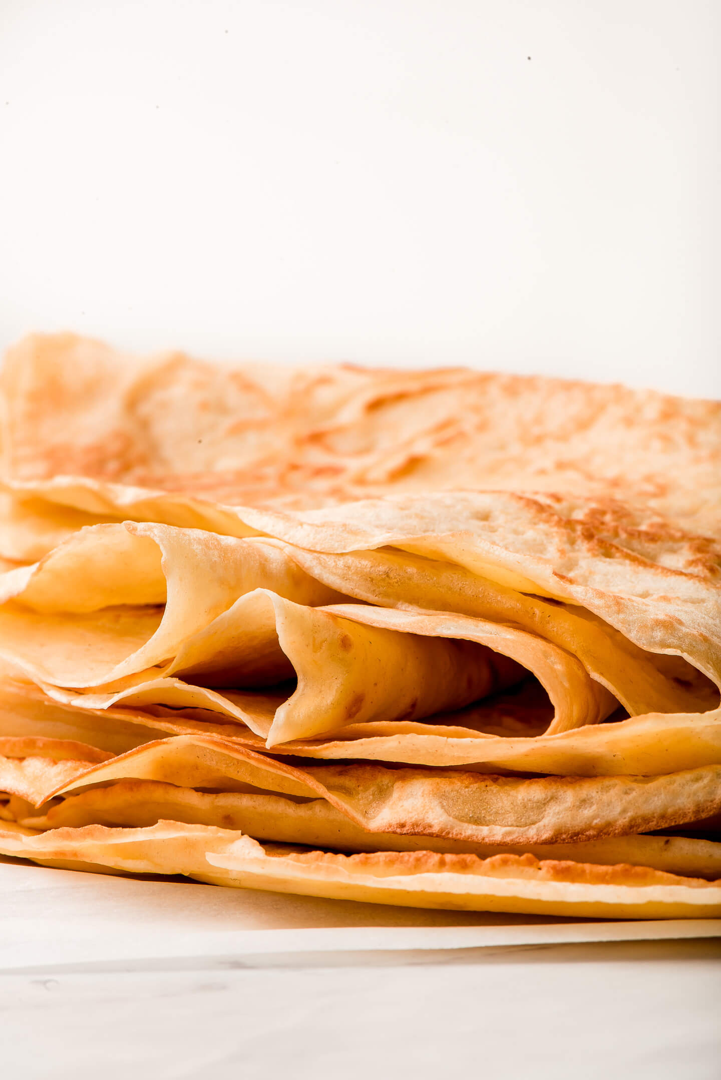 Close up side view of thin crepes stacked on top of each other.