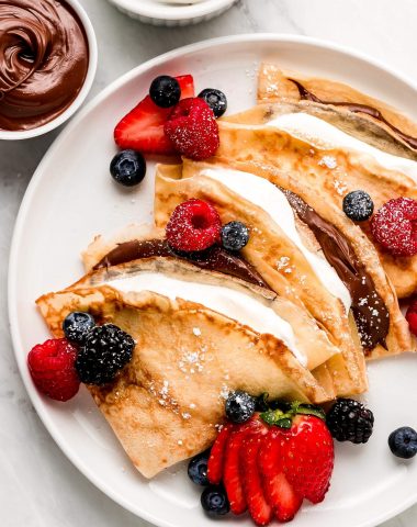 Close up of stuffed crepes with berries on top.