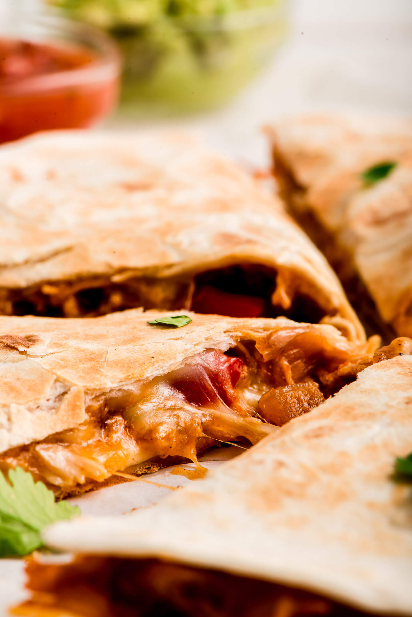 Close up side view of a quesadilla filled with cheese, chicken, and peppers.