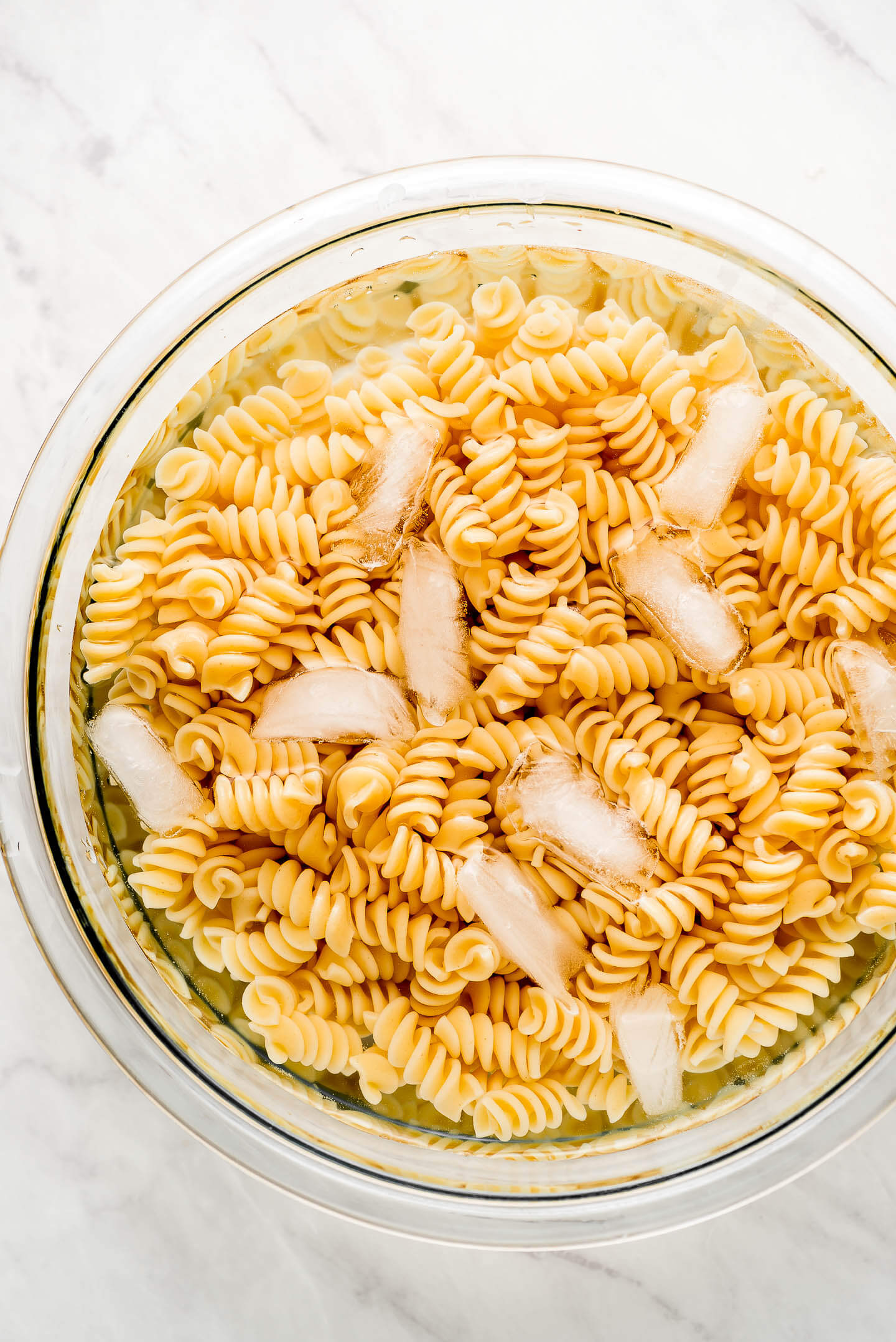 Cooked Rotini pasta in a bowl of ice water.