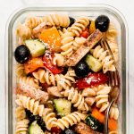 Pasta salad with chicken and vegetables in a glass meal prep container.