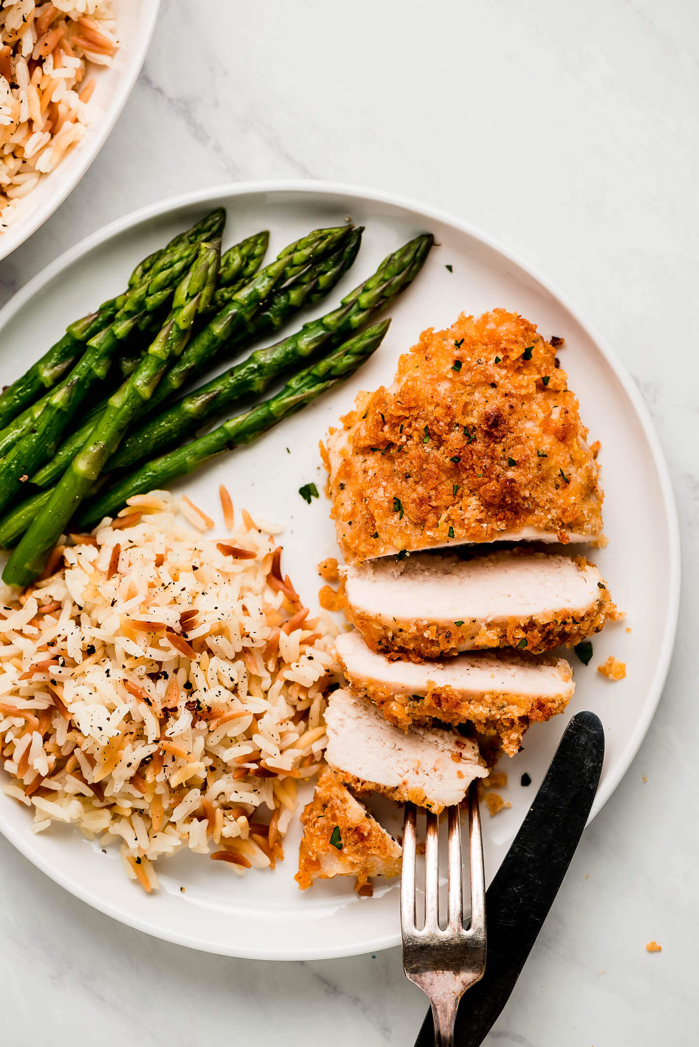 A plate of sliced Ranch Chicken, asparagus, and orzo rice.