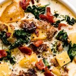 Two bowls of soup with sausage, potatoes, kale, and bacon.